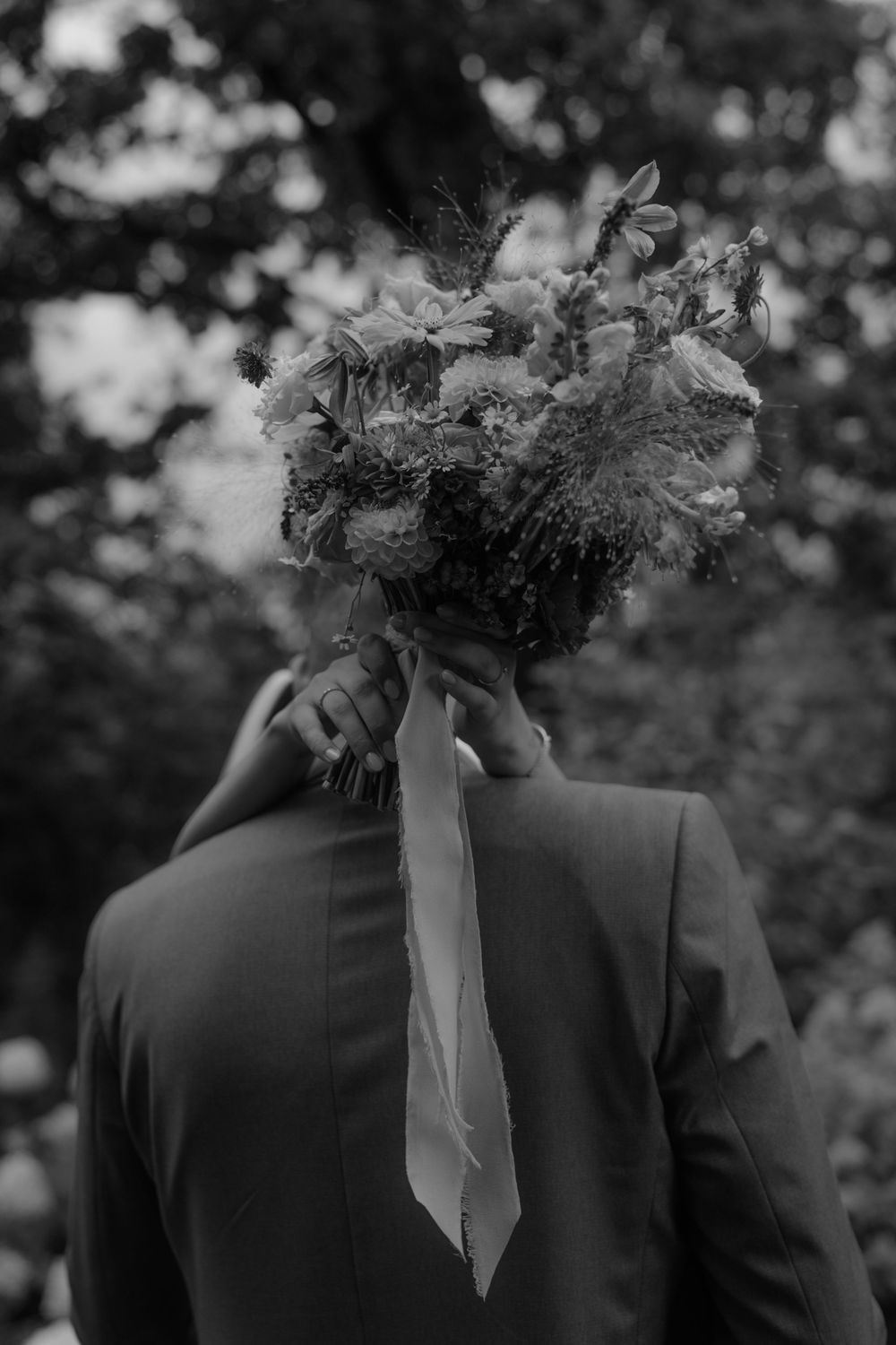 Black and white detail shot of groomsmen's suits with floral bouquet.