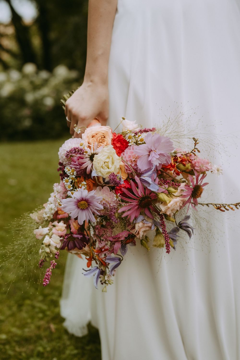 Close-up of pink and white wedding bouquet against white bridal gown.