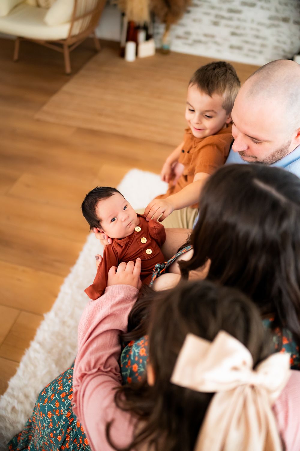Family spending quality time together sitting on a fluffy white rug in a cozy living room with hardwood floors.
