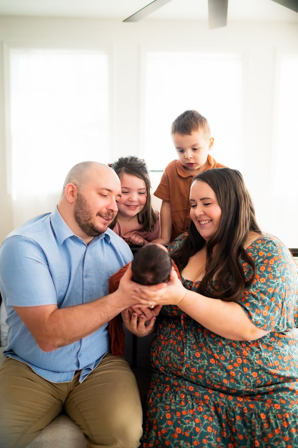 A happy family shares an intimate moment together while sitting on a couch in a bright room.