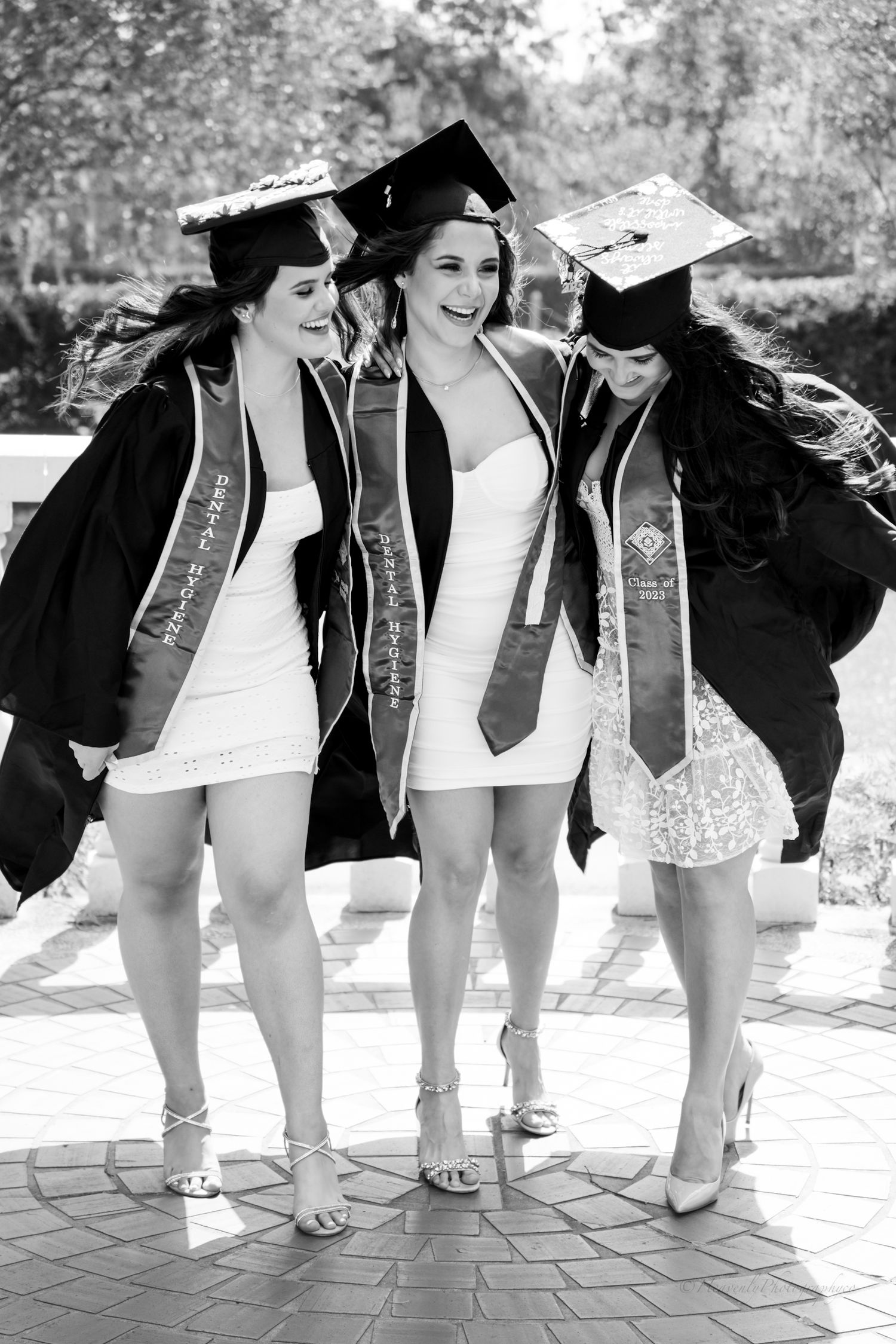 Row of graduates showing off their shoes and graduation stoles in black and white photo.