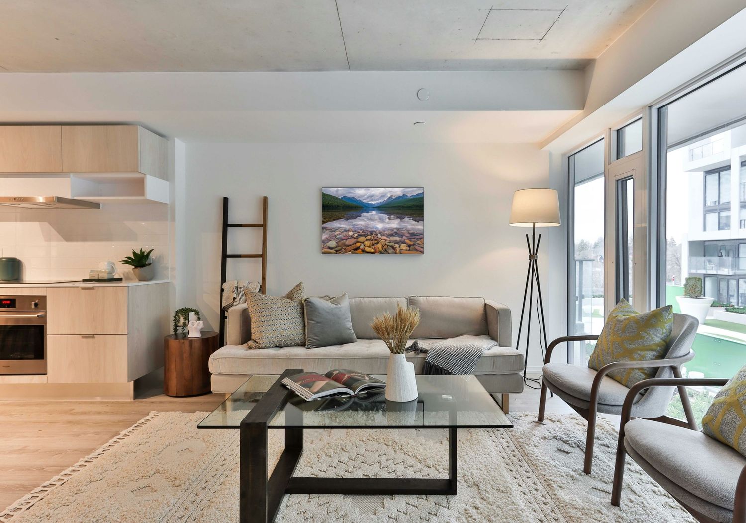 A modern living room with a fine art print on the wall. The print is an image of a mountain lake.