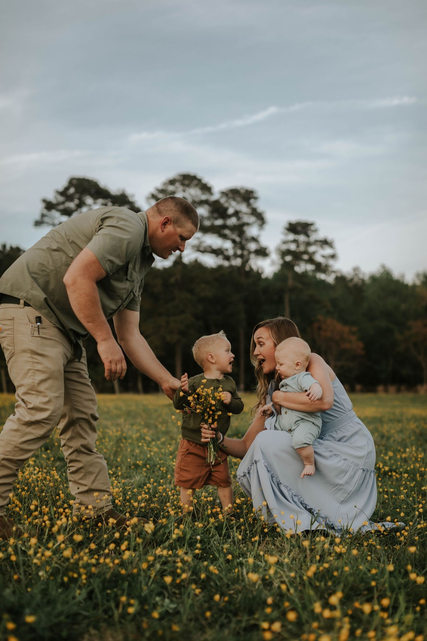 A couple sits together in tall grass during golden hour.