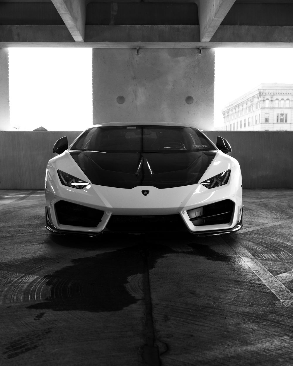 Black and white photo of a Lamborghini Huracan's aggressive front end in a dark parking garage.