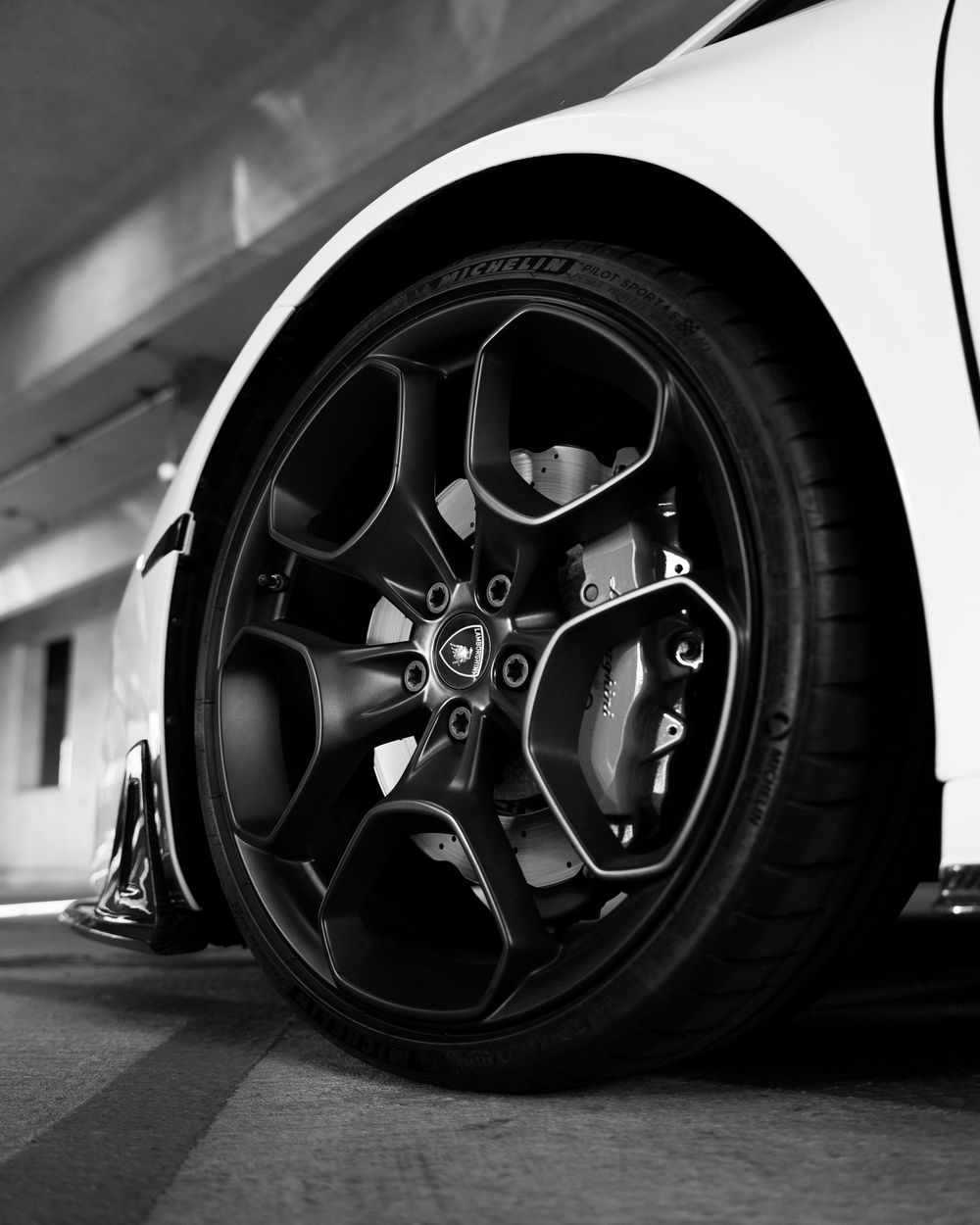 Black matte performance wheel with five-spoke design and low profile tire mounted on a luxury vehicle.