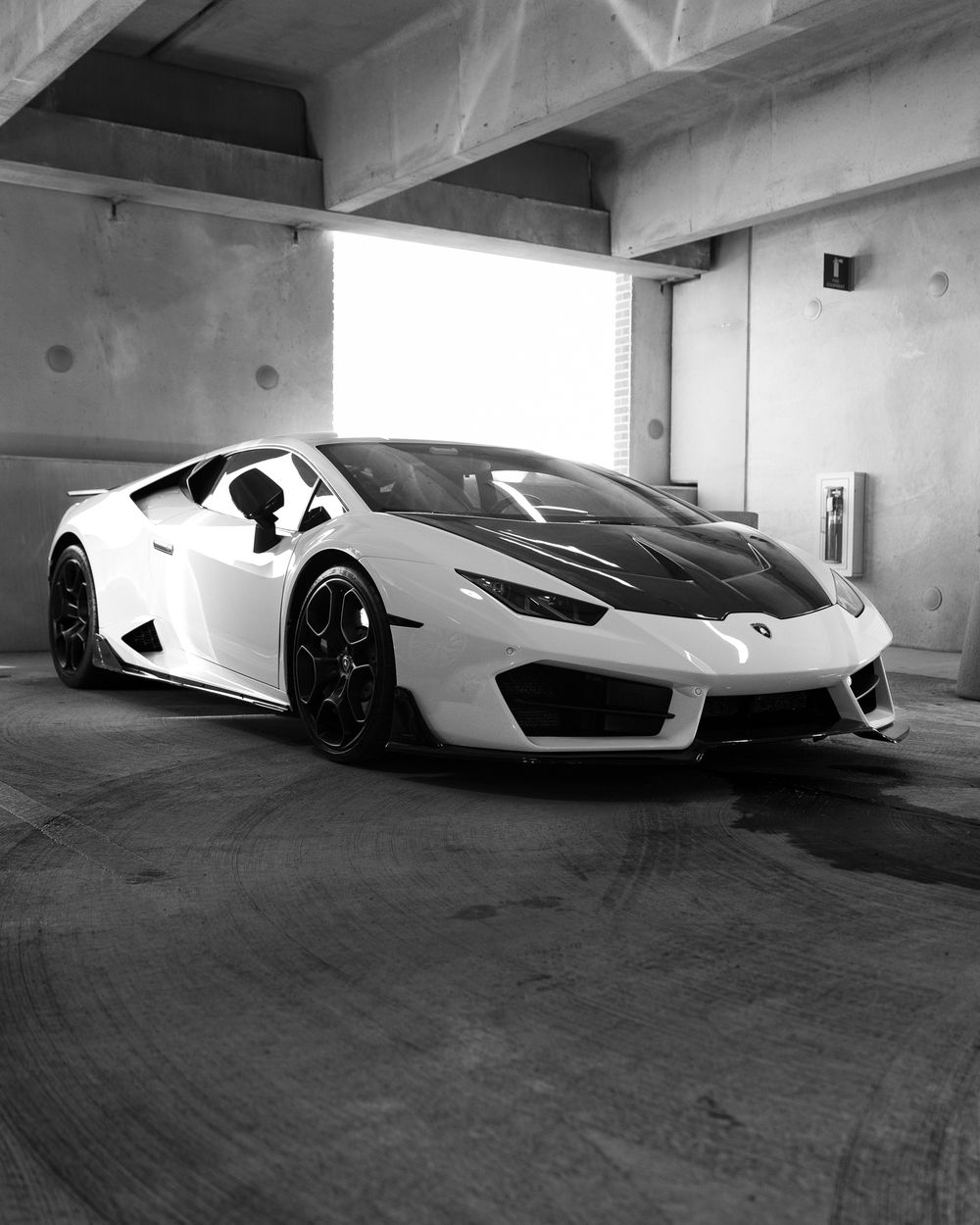 A sleek white supercar photographed from multiple angles in a minimalist concrete garage space.