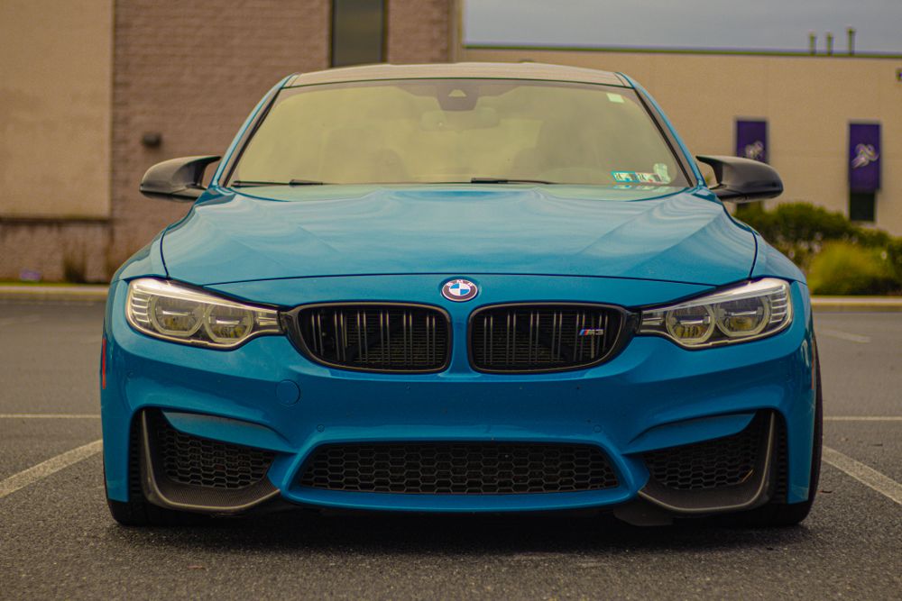 Front end detail shots of a blue BMW M4 showing aggressive styling and signature kidney grilles.