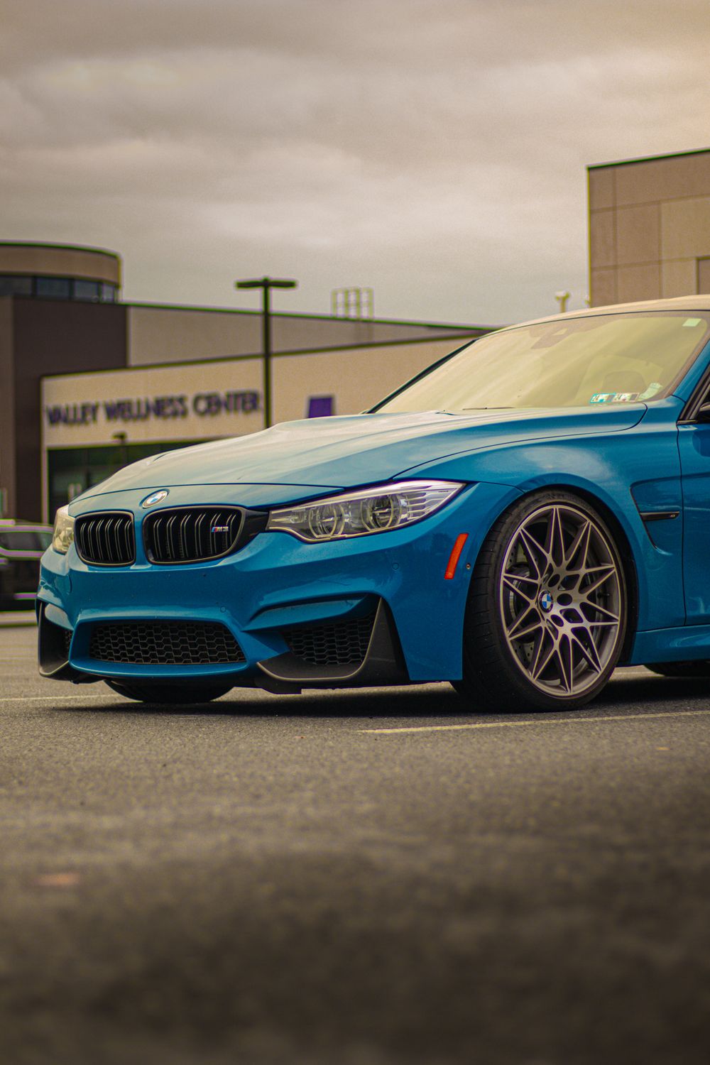 Low profile shots of a modified BMW M4 in bright blue showcasing its lowered stance.