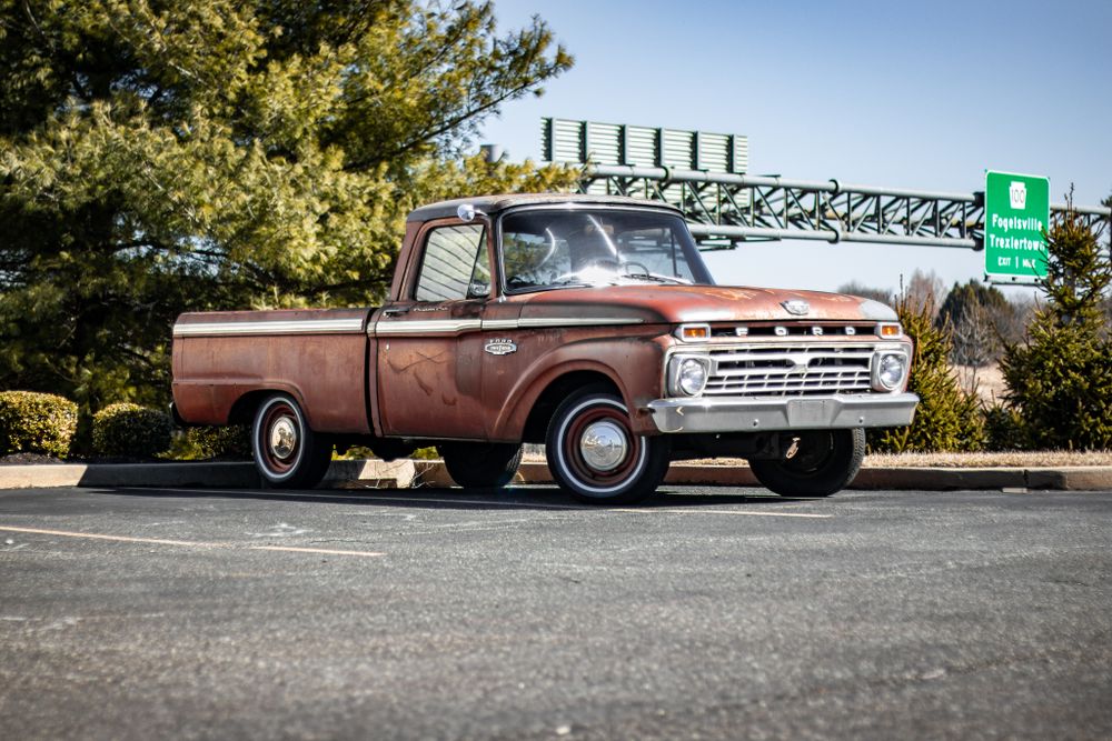 Vintage pickup trucks and classic cars lined up in a parking lot.