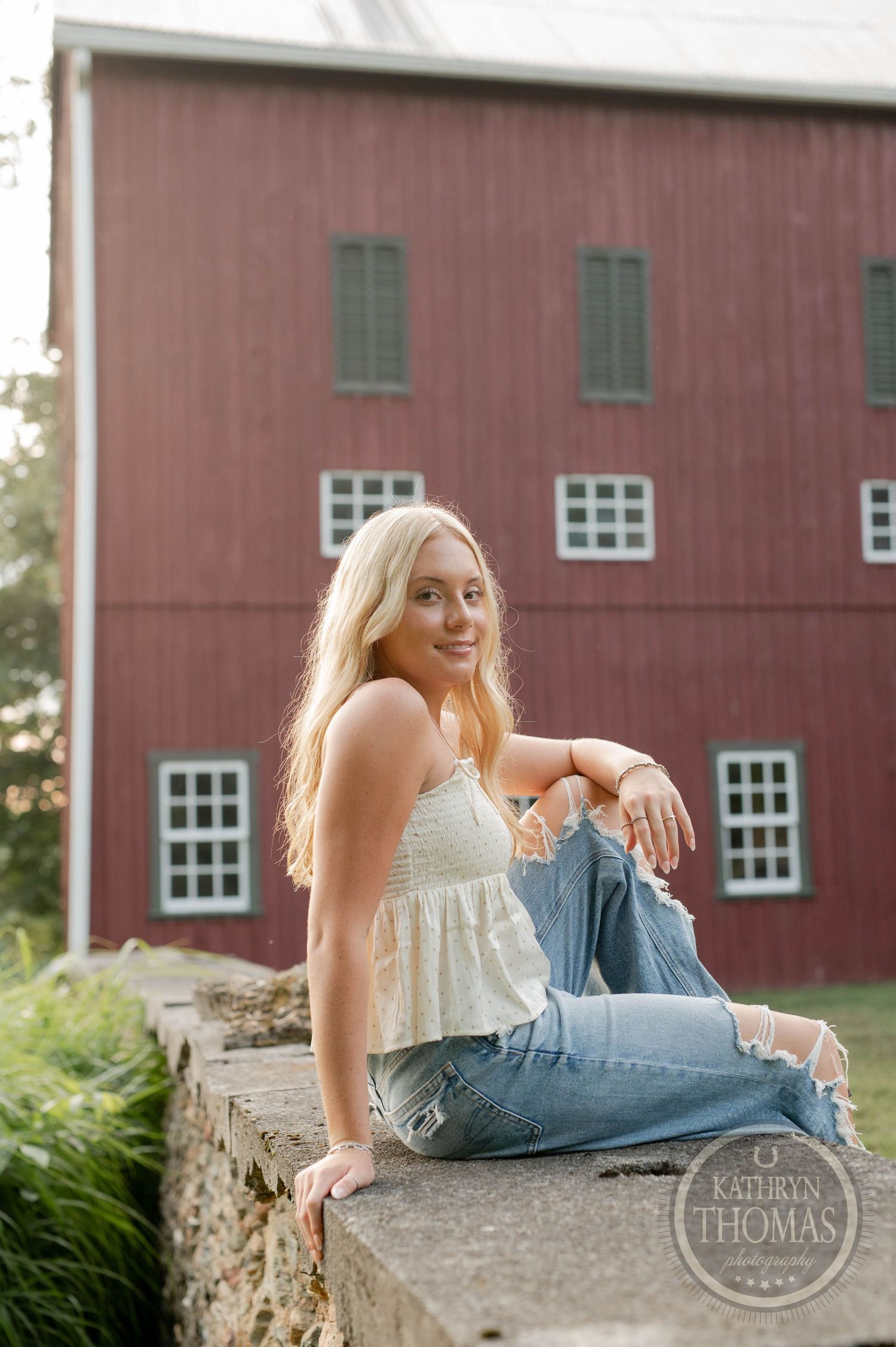 Vintage-style portrait against classic red barn with white windows.