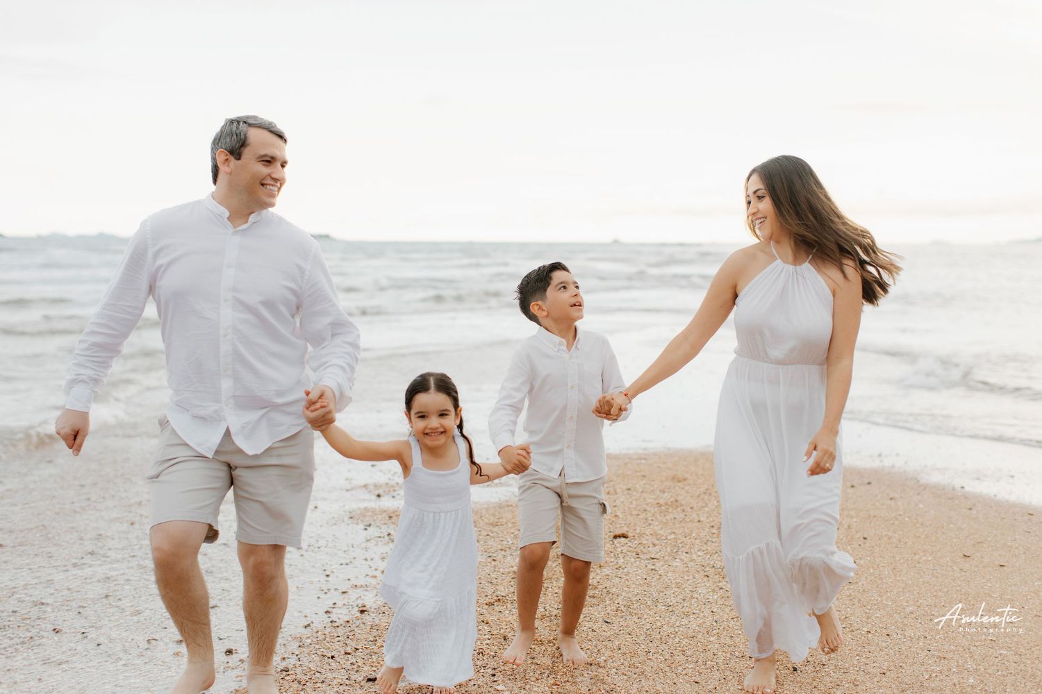 A cheerful family running and playing together on a sunny beach.