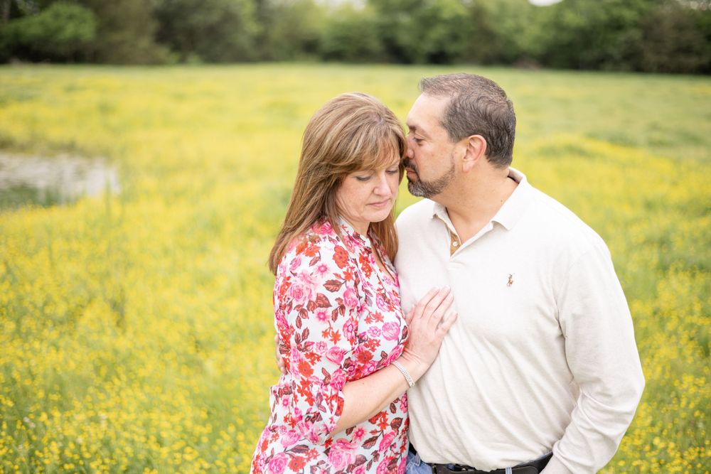 A couple shares a tender moment in a field of yellow wildflowers on a warm spring afternoon.