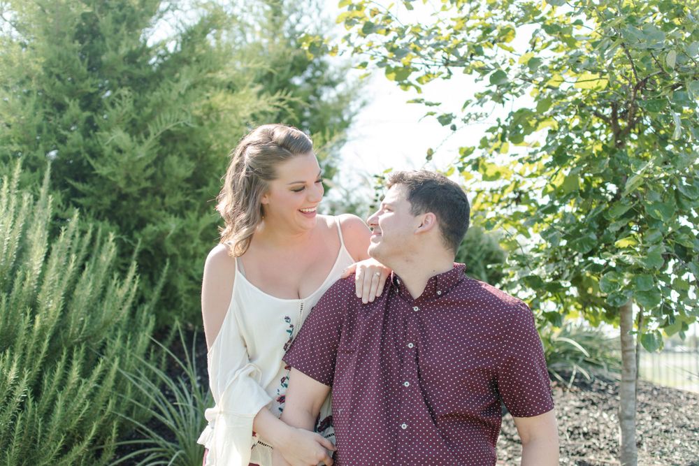 A cheerful young couple enjoying a sunny moment together in a lush garden setting.