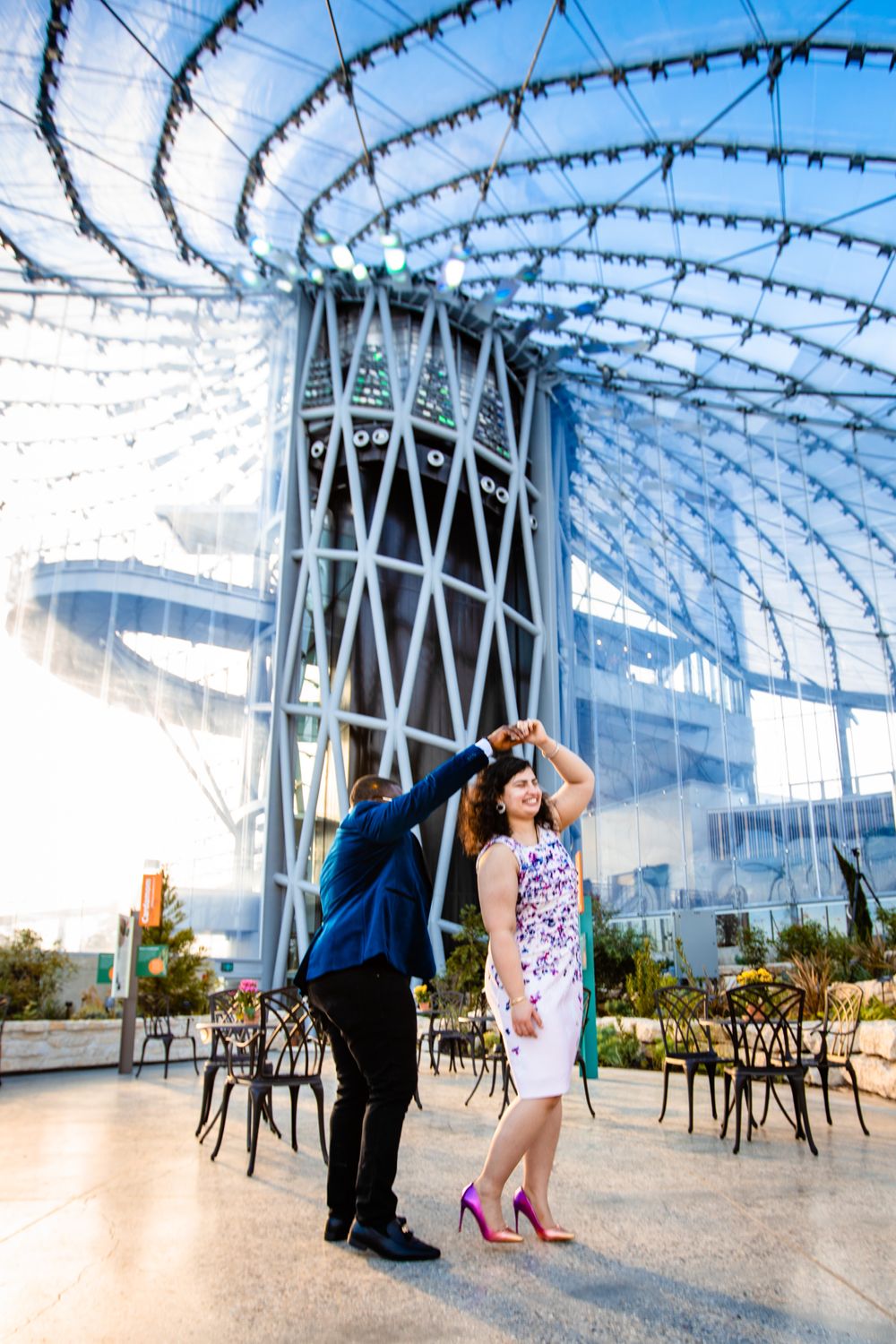 Couple dancing under an elegant glass-domed structure with geometric patterns.