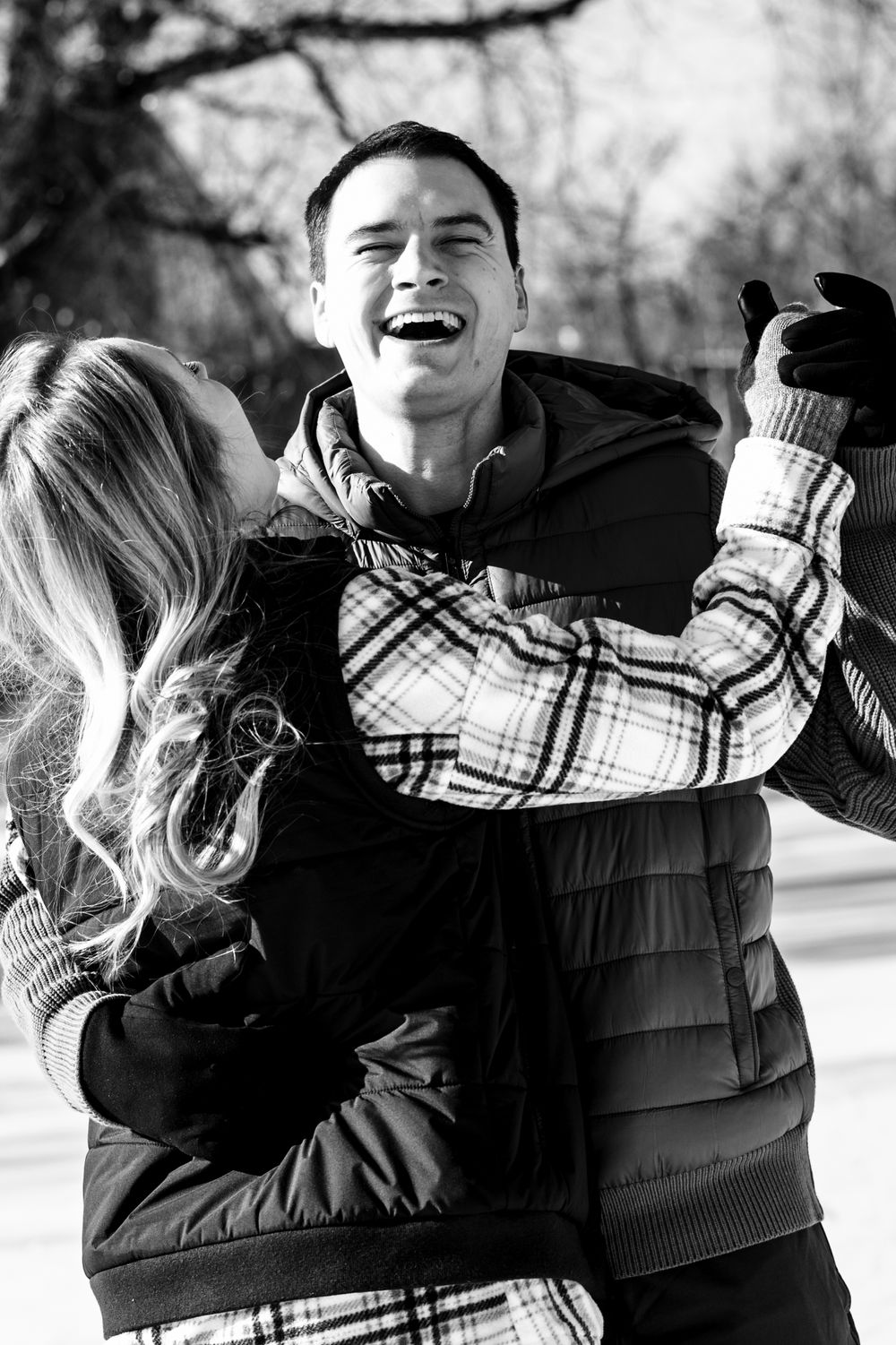 A candid black and white photo captures a joyful embrace during winter.