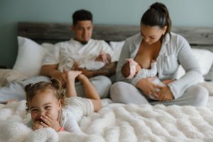 Family relaxes together on white bedding as they enjoy a peaceful morning at home.