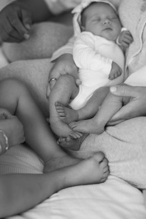 A black and white closeup of infant feet and legs resting on soft bedding.