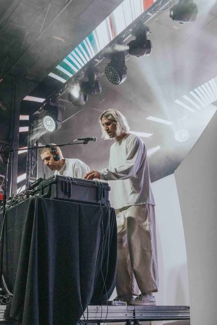 Electronic music performers on stage with dramatic lighting and fog effects during a live concert performance.
