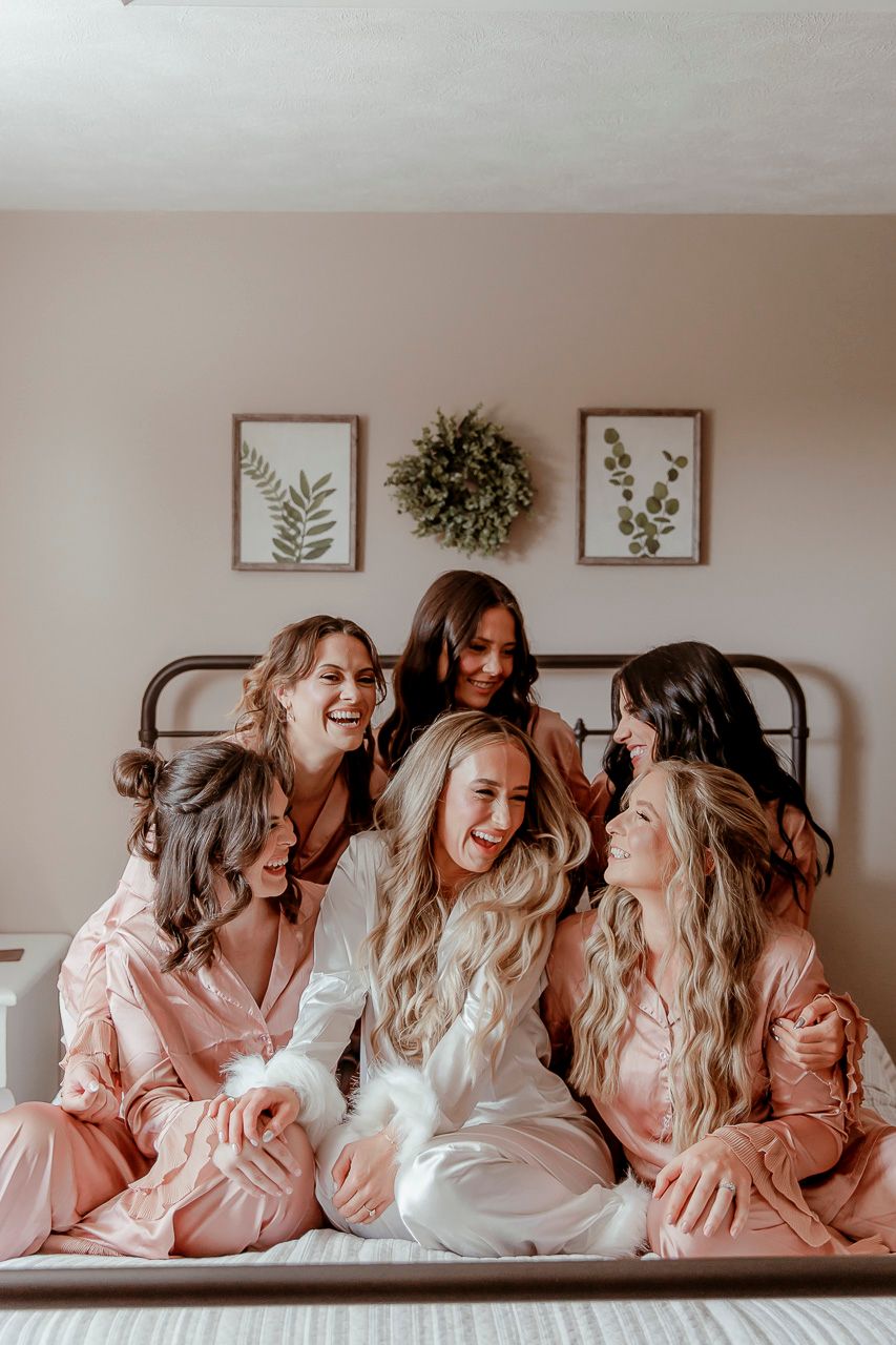 Candid moment of joy shared on a bed with botanical prints and wreath hanging on wall behind.