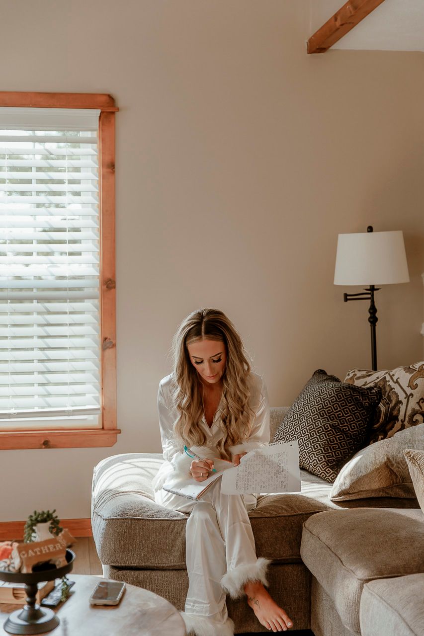 Person relaxing on a grey couch in a cozy living room with natural light from window and warm wooden accents.