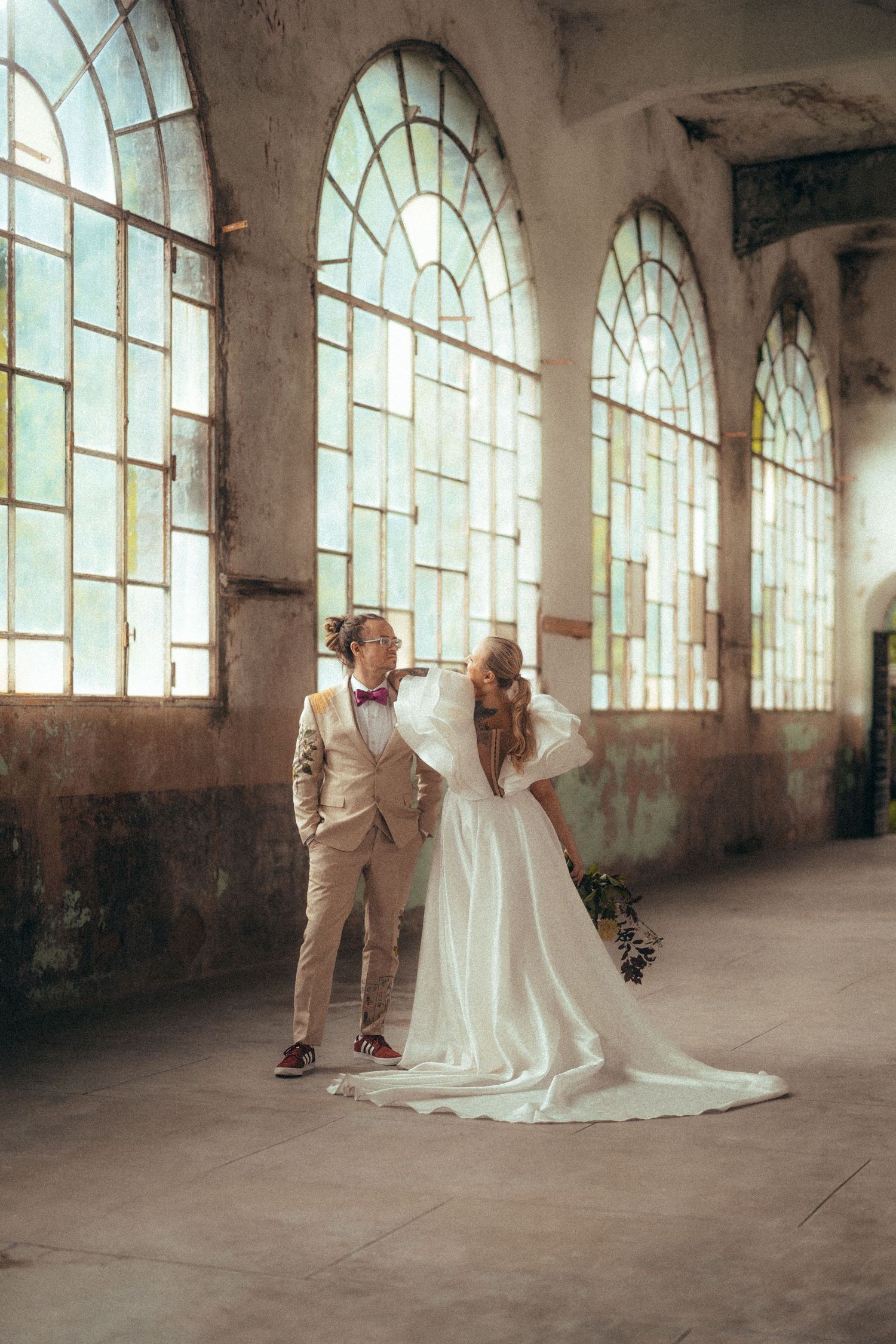 Wedding couple poses in dramatic archway with natural light in black and white.
