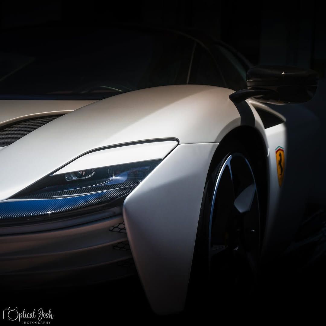 Close-up detail shot of a sleek silver McLaren supercar's front headlight and hood.
