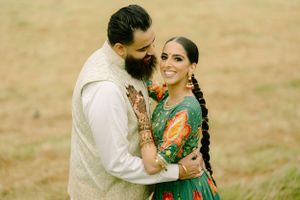 Couple in traditional Indian attire embrace lovingly in a warm field during golden hour.