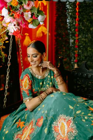 Indian wedding decor features ornate floral arrangements and decorative swing against vibrant red backdrop.
