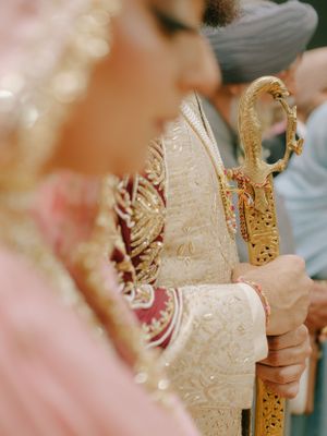 Traditional gold ceremonial staff with intricate details held during a formal cultural event in soft focus.