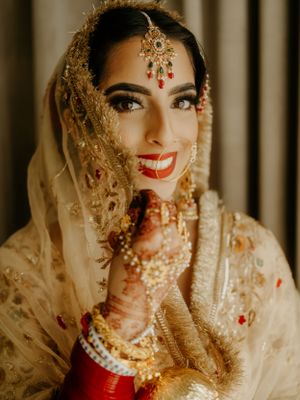 Close-up portrait showcasing intricate bridal jewelry and traditional Indian wedding makeup.
