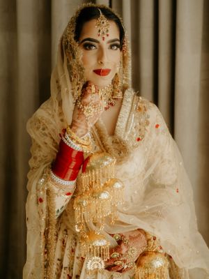 Traditional Indian bridal portrait highlighting gold jewelry and red chooda bangles.