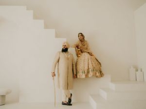 Artful sepia-toned wedding portrait on white staircase showcasing couple's elegant attire.