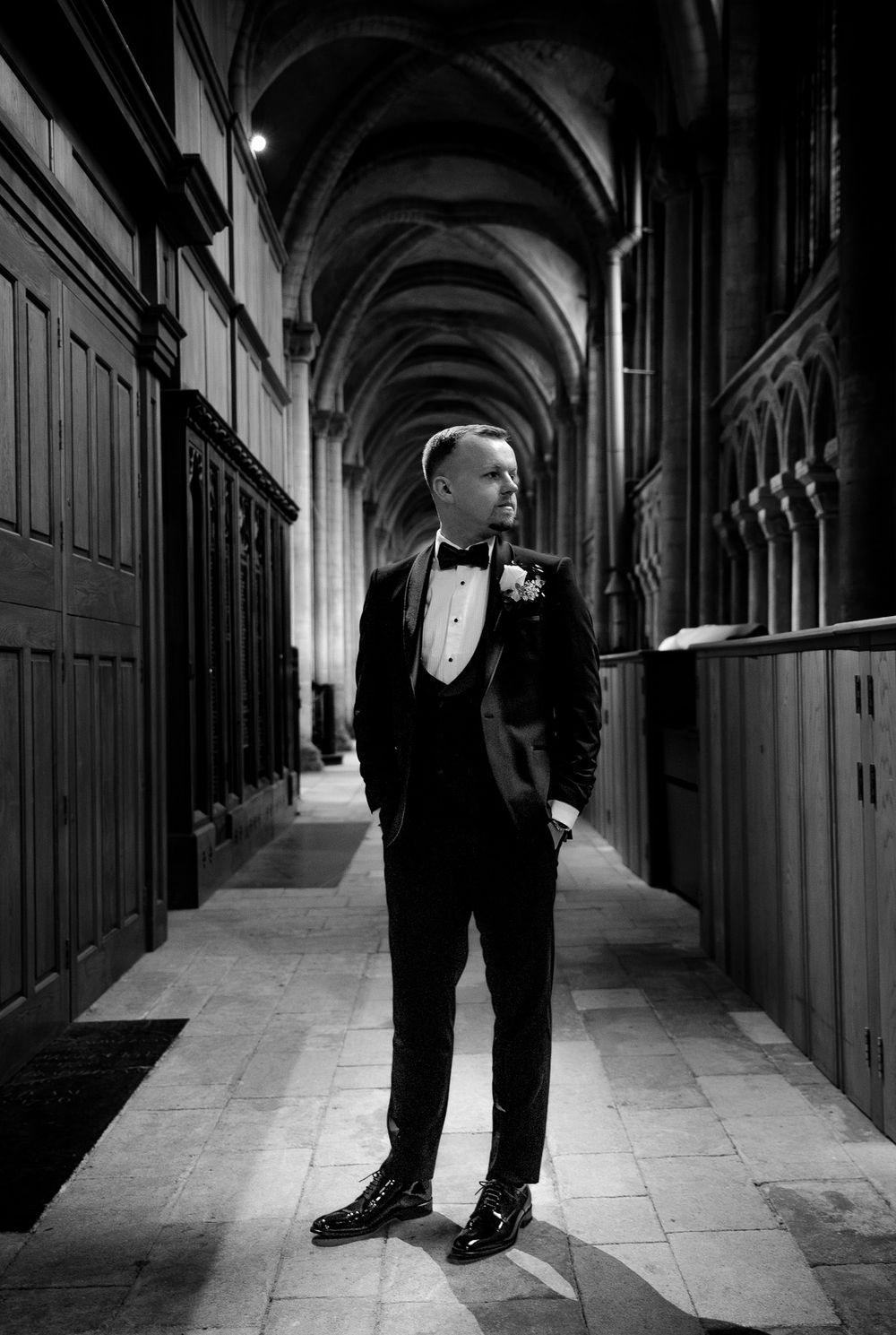 Black and white photo of formal shoes in a dramatic cathedral hallway with arched ceilings.