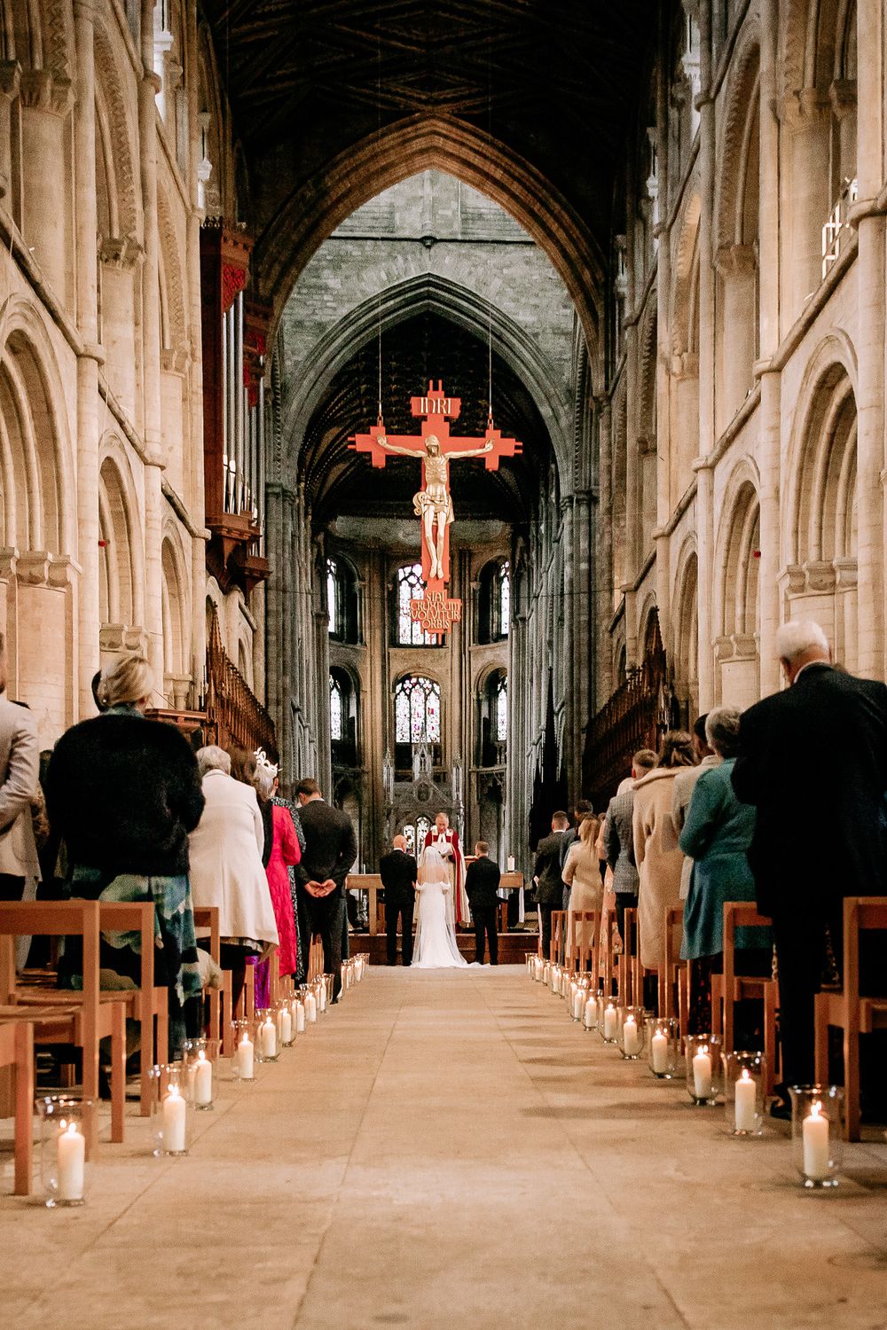 Cathedral interior with wooden pews and gothic architecture during a wedding ceremony.
