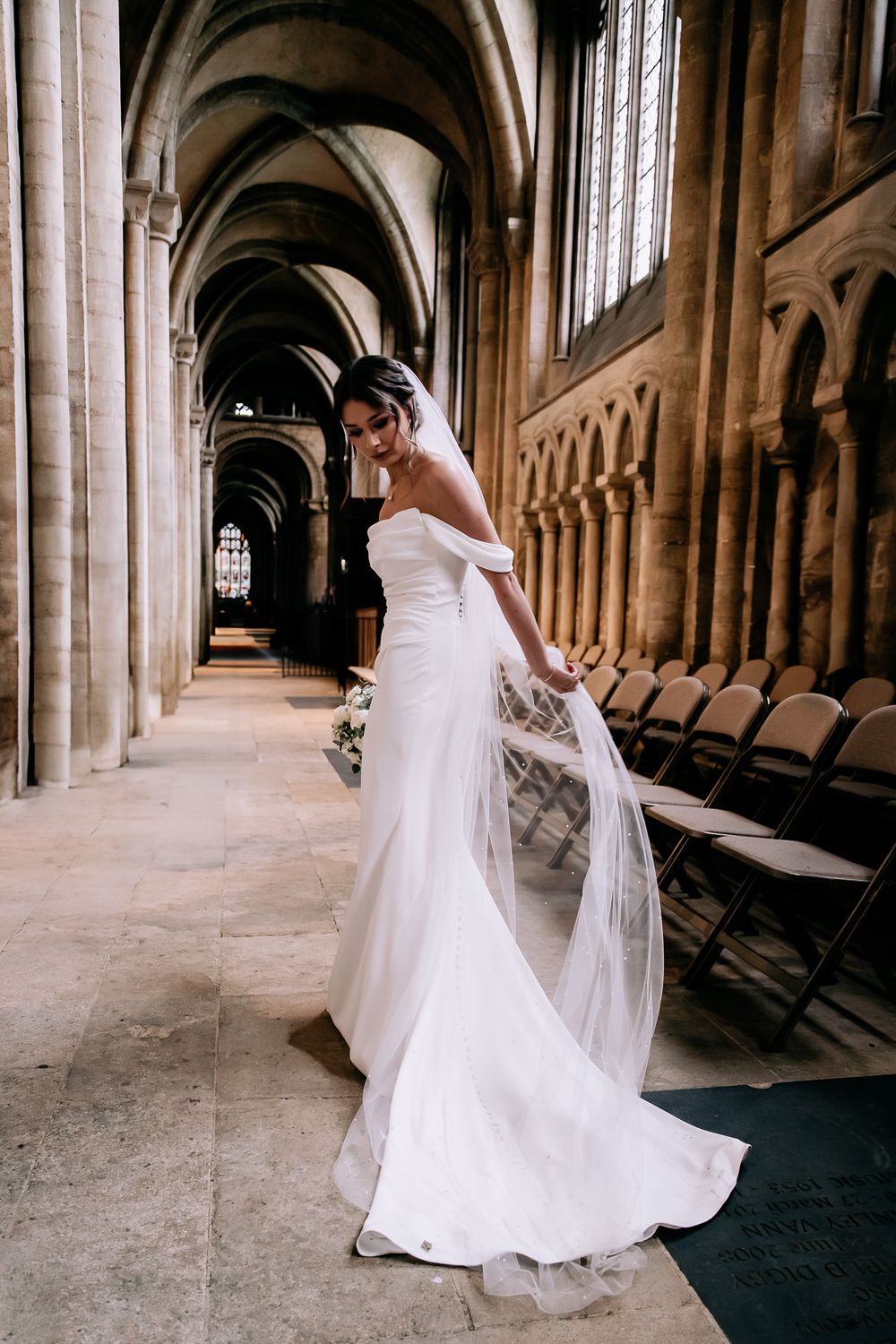 A bride twirls in a flowing white wedding dress inside a grand cathedral with soaring stone archways.