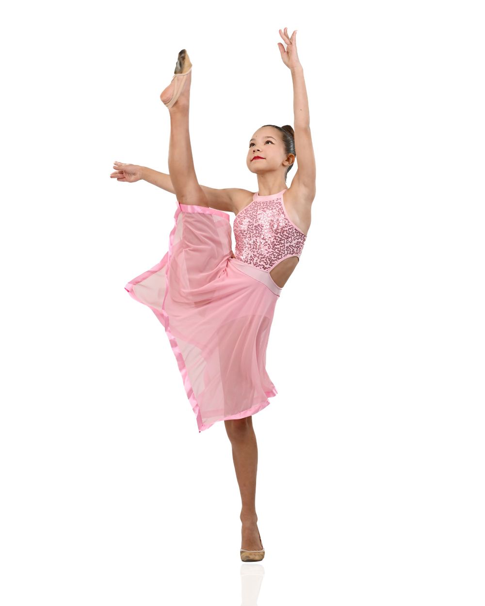 Dancer in pink sequined costume performs graceful ballet pose with one leg extended high while balancing en pointe.
