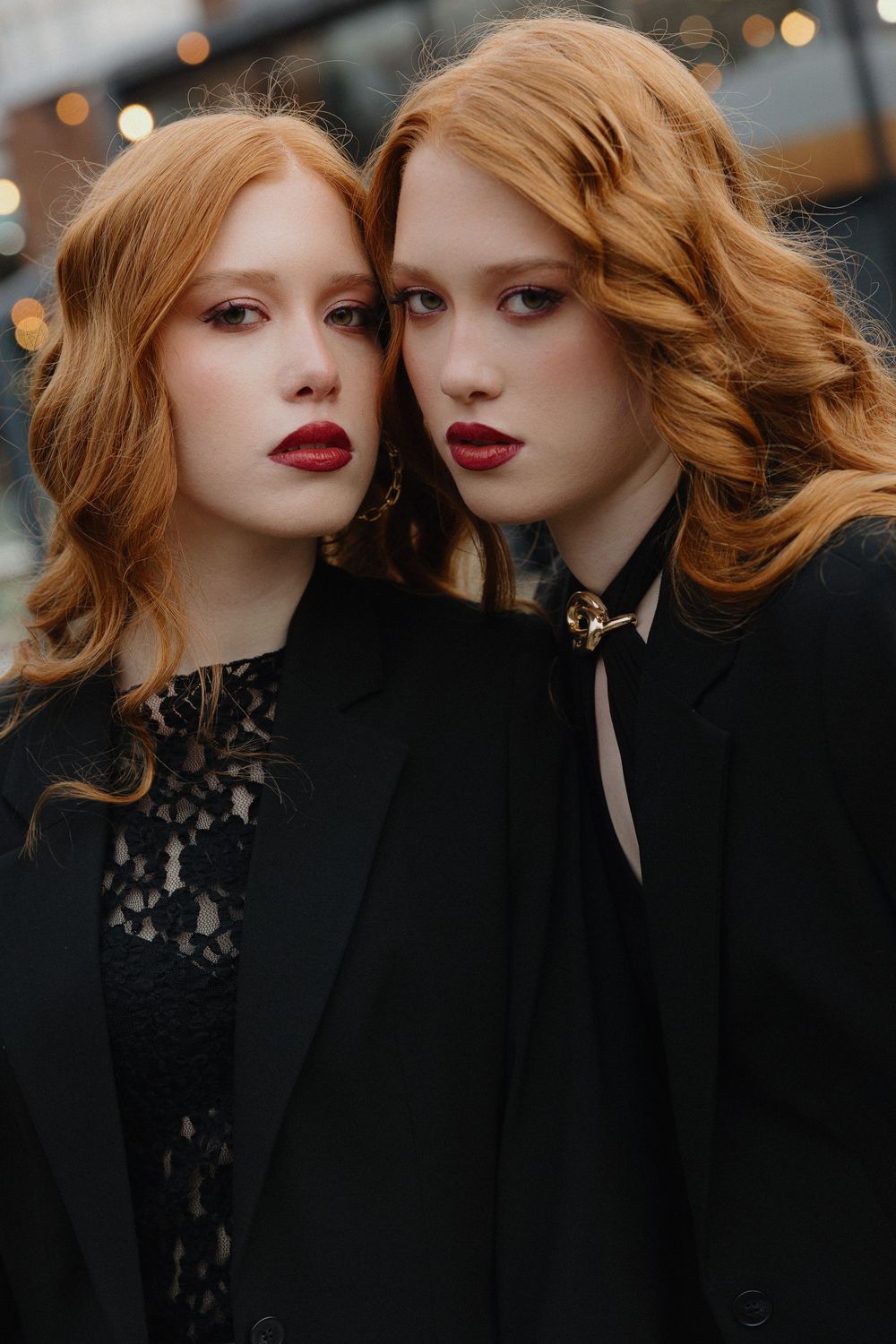 Moody fashion portrait with dark lipstick and black lace clothing against bokeh lights.