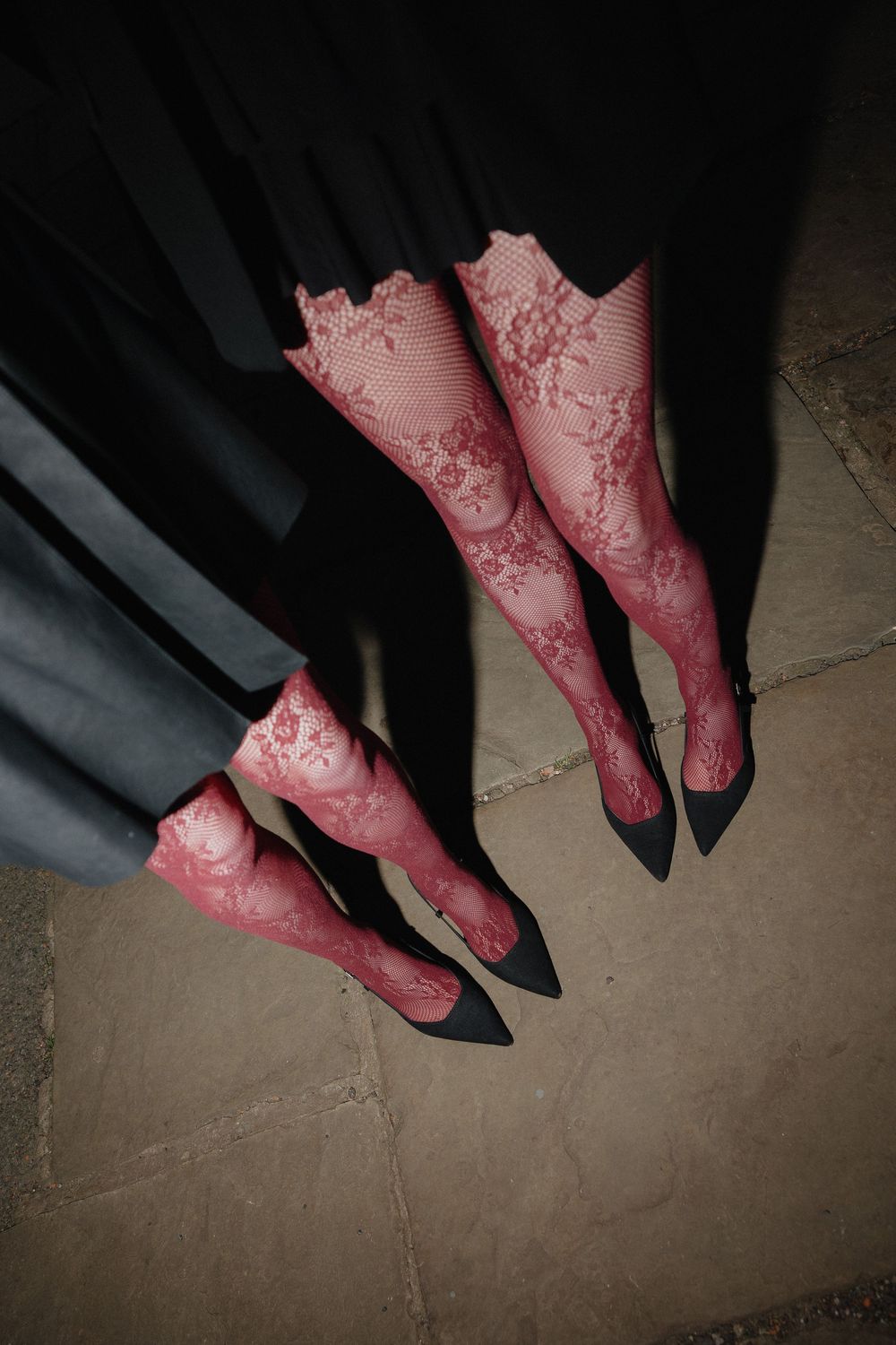Pink patterned stockings and black shoes captured in a sequence of walking steps on a neutral floor.