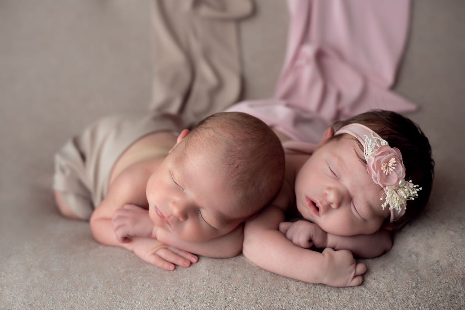 Delicate newborn photography featuring soft pink tones and gentle natural poses of twin newborn babies.