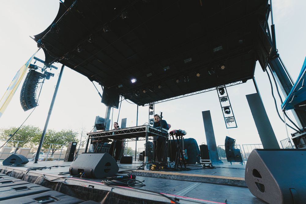 Wide-angle shot of stage rigging and technical equipment being set up for an outdoor performance venue.