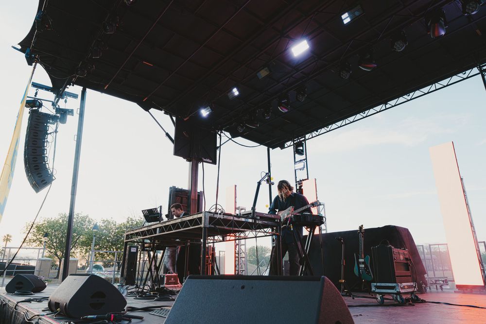 A large outdoor stage setup with lighting equipment and speakers under a dark sky.