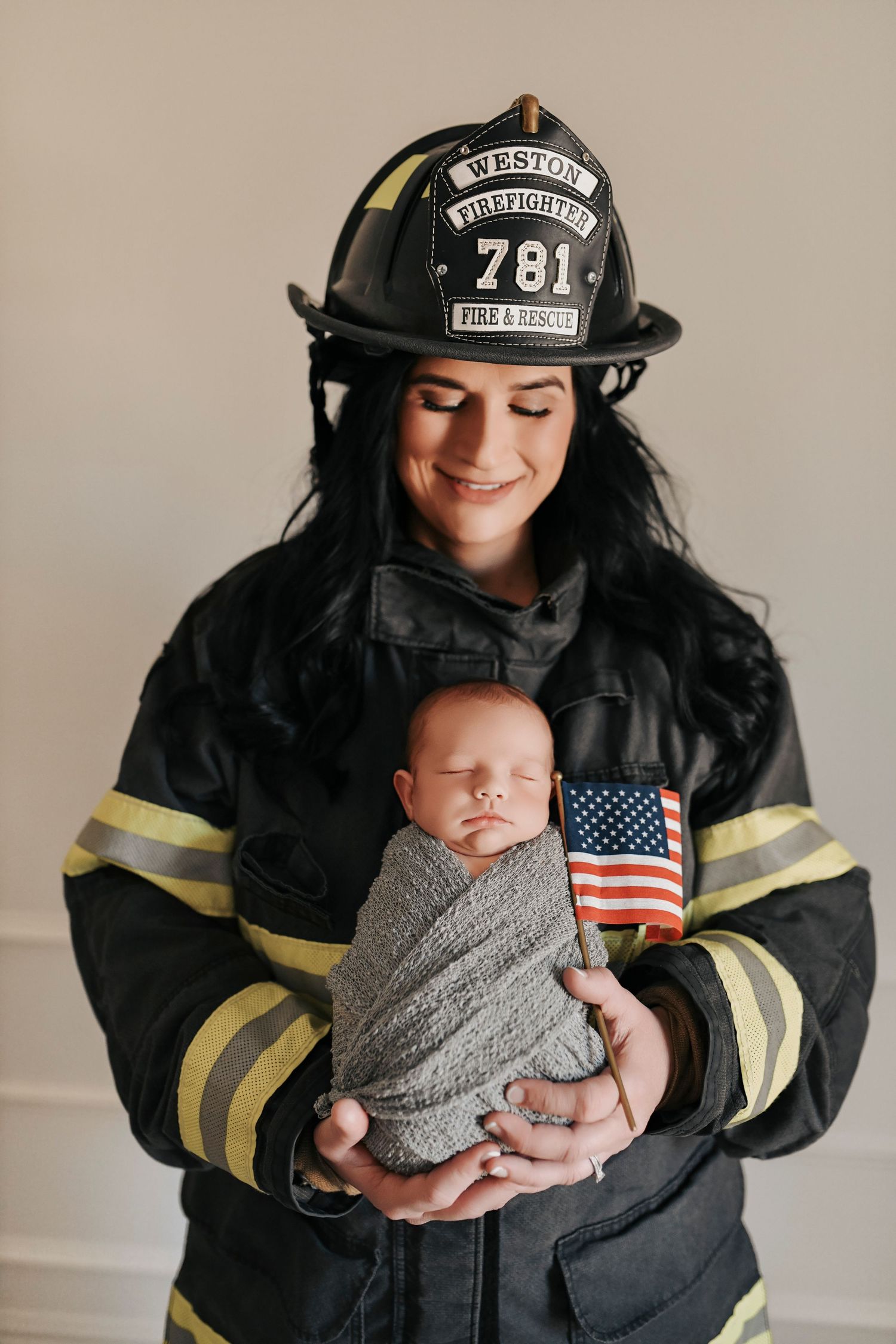 Firefighter mom in uniform holding her newborn baby close during an emotional studio newborn session in Denton, Texas