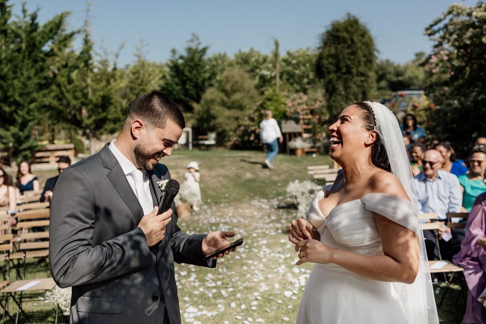 A happy couple shares a joyful moment during their outdoor wedding ceremony with guests looking on.
