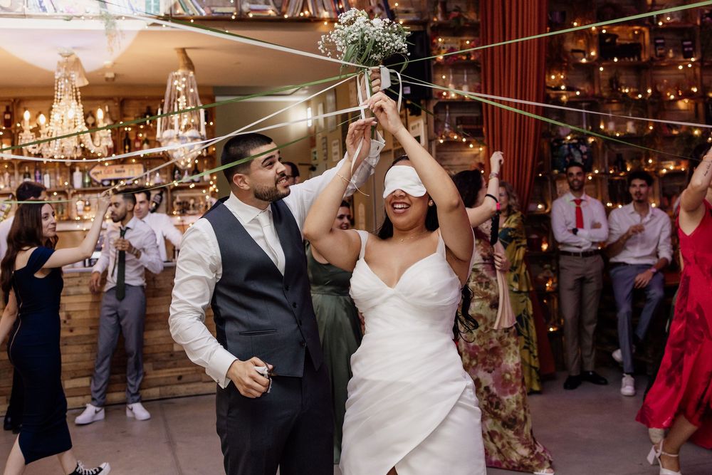 Wedding couple dances together in a rustic barn venue decorated with twinkling lights and chandeliers.