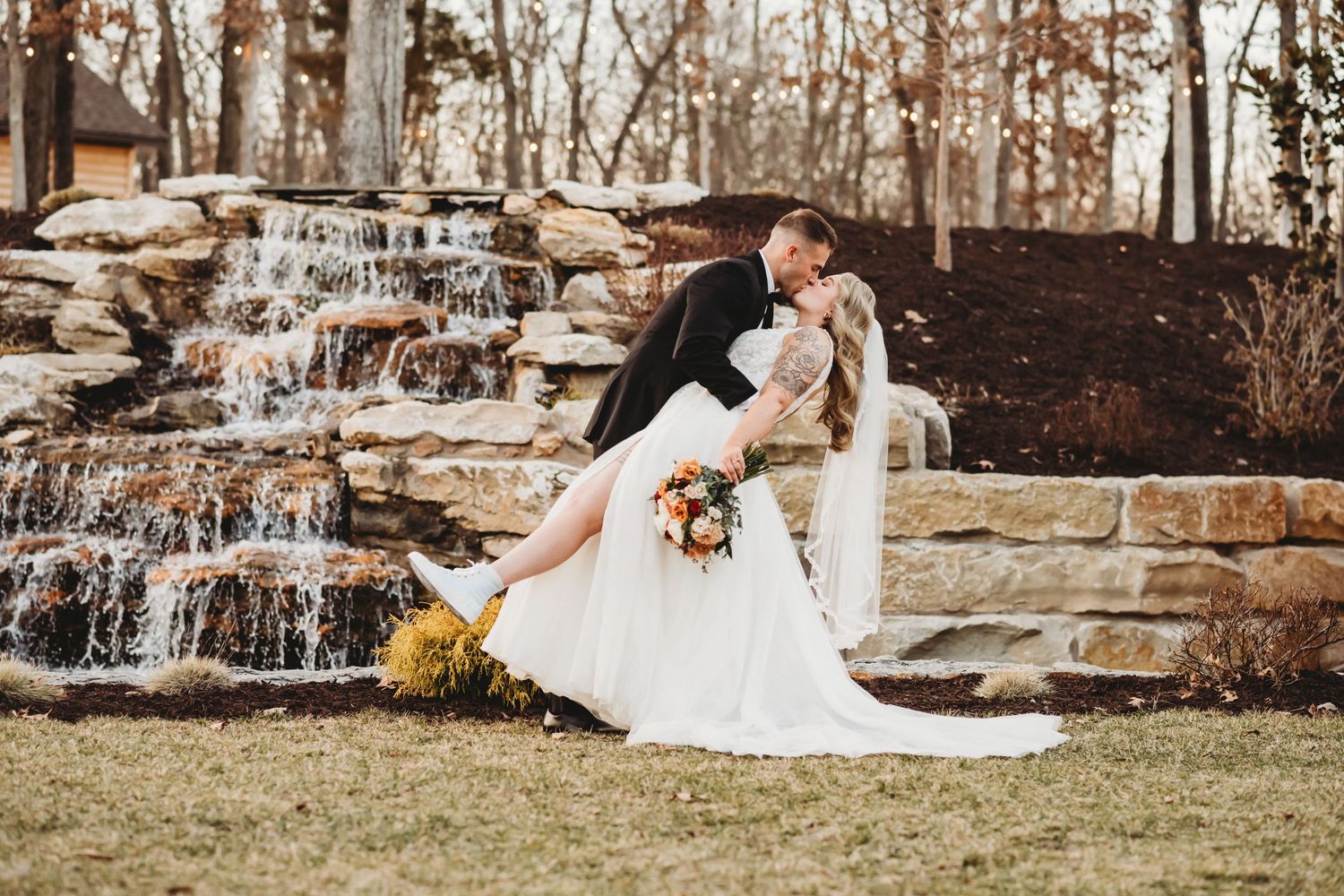 groom dips bride and kisses her while she is holding her bouquet