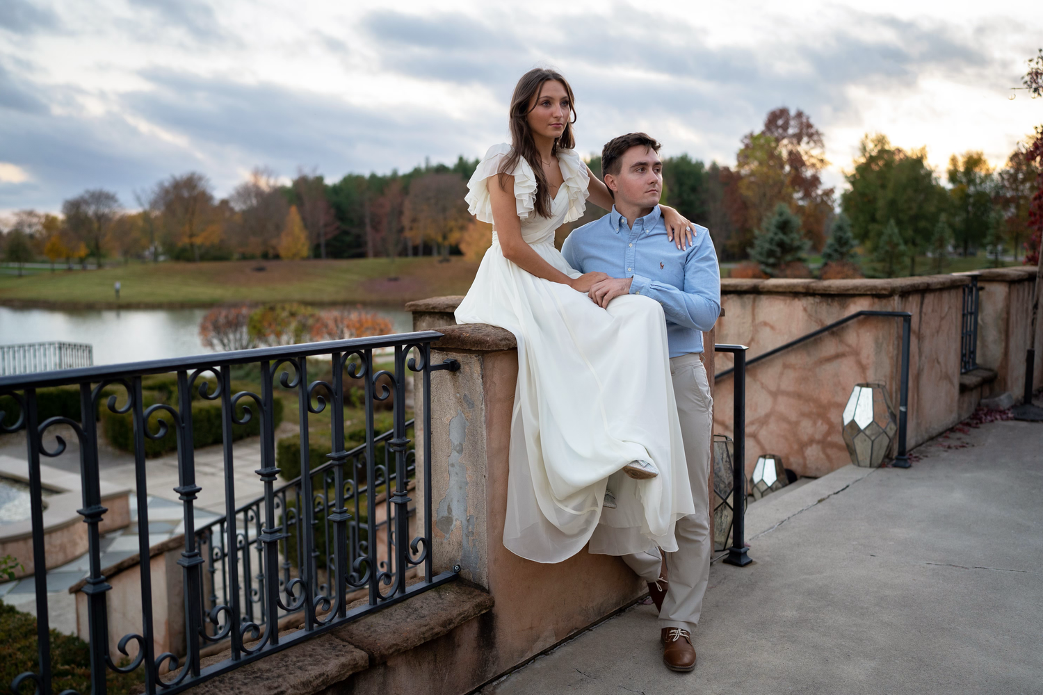 classic couple sits together on a stone balcony during engagement session