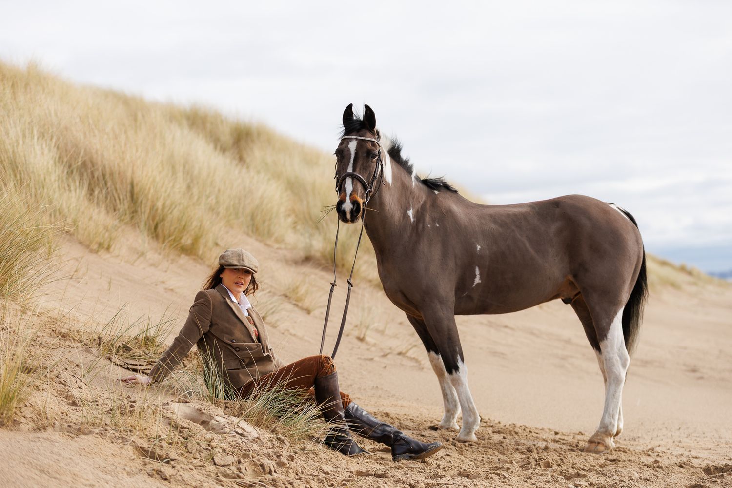 A horse and its rider enjoy an outdoor photoshoot session near rustic wooden fencing on a sunny day.