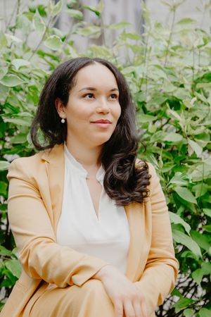 Woman in yellow blazer and white top poses outdoors against green foliage background in multiple candid shots.
