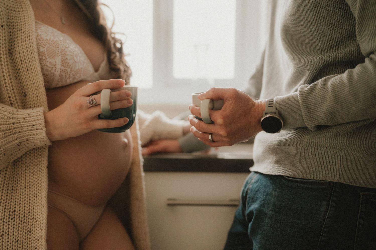 A pregnant woman and her partner sharing a tender moment together near a window.