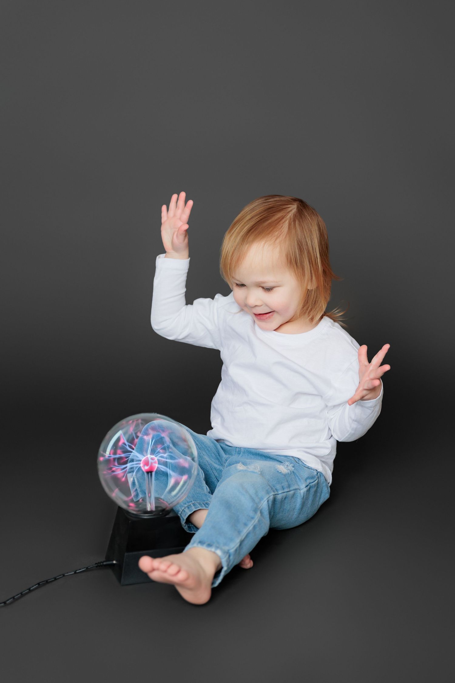 A series of playful poses captured against a dark background shows someone in jeans and white shirt lying down.